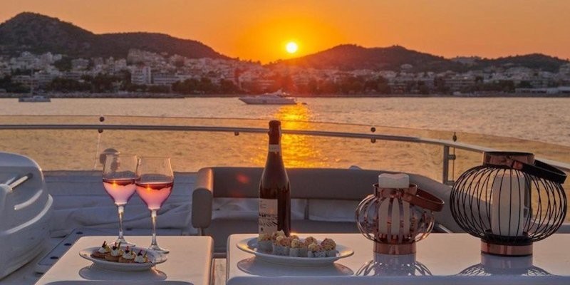 Sun setting over island mountains, yacht dining table in foreground