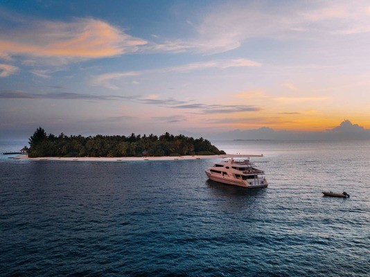 Luxury catamaran anchored in the sea off a tiny Maldives island